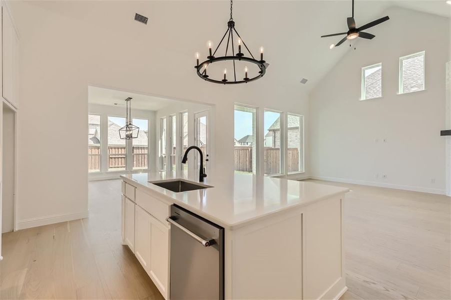 Kitchen featuring plenty of natural light, a center island with sink, stainless steel dishwasher, sink, and pendant lighting