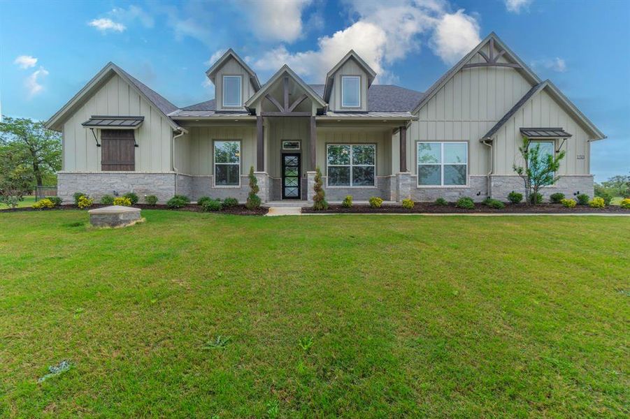 Craftsman-style house with board and batten siding, a porch, a front yard, and stone siding Craftsman-style house with board and batten siding, a porch, a front yard, and stone siding