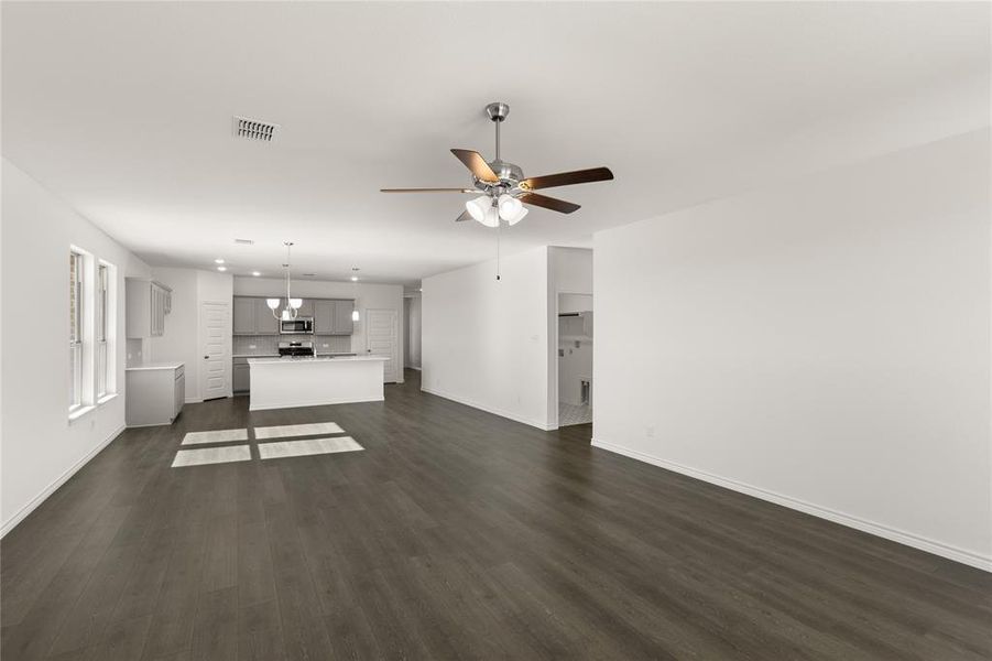 Unfurnished living room featuring ceiling fan and dark wood-type flooring