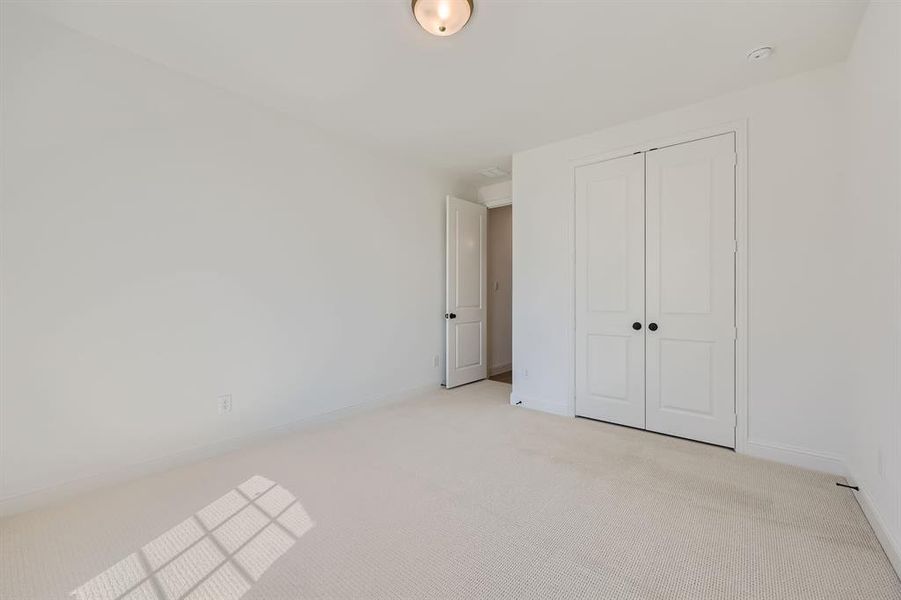 Unfurnished bedroom featuring light carpet and a closet