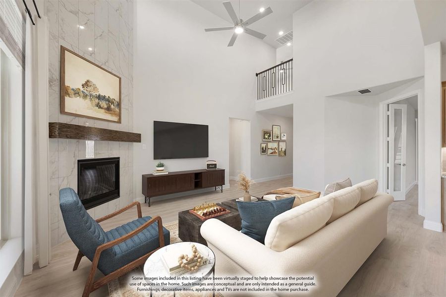 Living room with two-story ceiling, marble fireplace, ceiling fan, and open second-floor balcony overlook