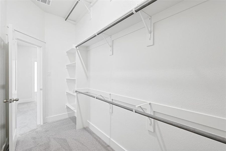 The property features a walk-in closet with carpeted flooring, white walls, and built-in shelving