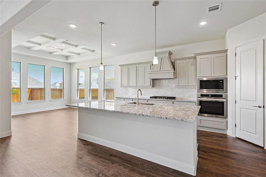 Kitchen featuring appliances with stainless steel finishes, coffered ceiling, dark wood-type flooring, light stone counters, and gray cabinets