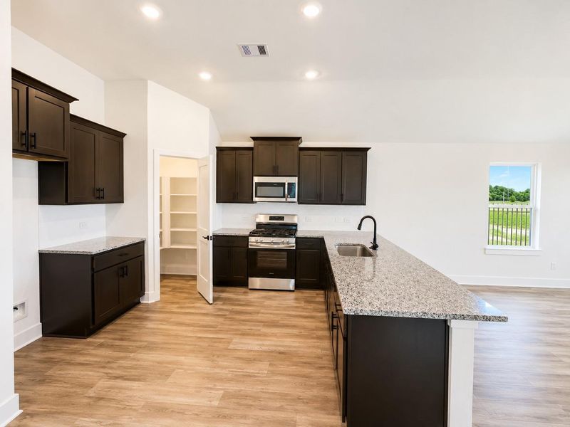 Modern kitchen featuring granite countertops, dark cabinetry, stainless steel appliances, a spacious island, and an open-concept layout perfect for entertaining.