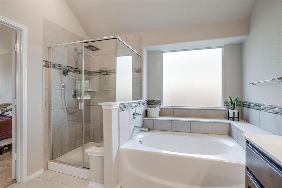 Bathroom with tile patterned flooring, vanity, plenty of natural light, and lofted ceiling