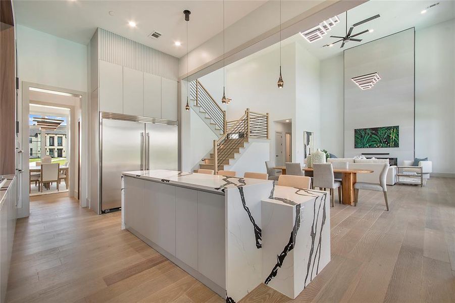 Living room featuring a high ceiling, light wood-style floors, stairway, and recessed lighting
