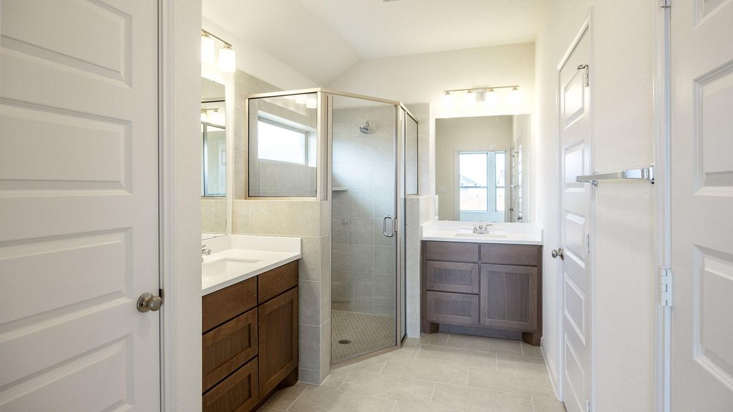 Bathroom with vanity, a shower with shower door, and tile patterned flooring