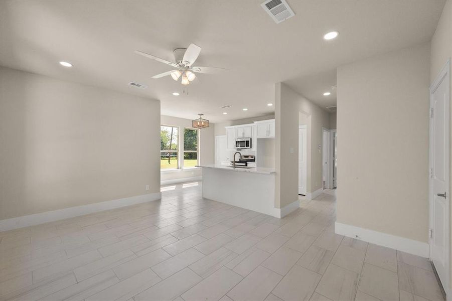 Unfurnished living room featuring sink, light tile patterned floors, and ceiling fan