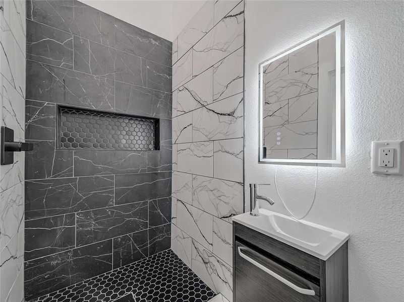 Bathroom featuring a tile shower and vanity