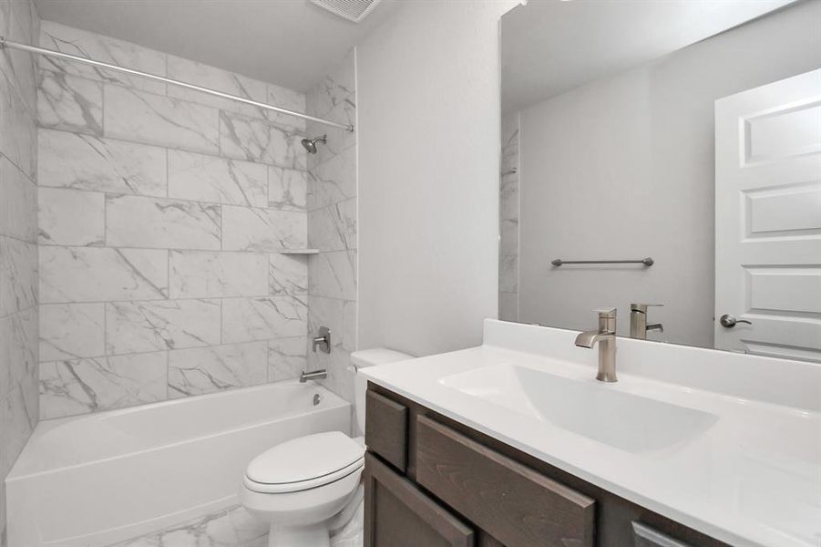 Secondary bathroom. Bath/shower combo with tile surround, dark wood cabinets complete with a beautiful light countertop, this bathroom combines style and functionality for a truly inviting ambiance.