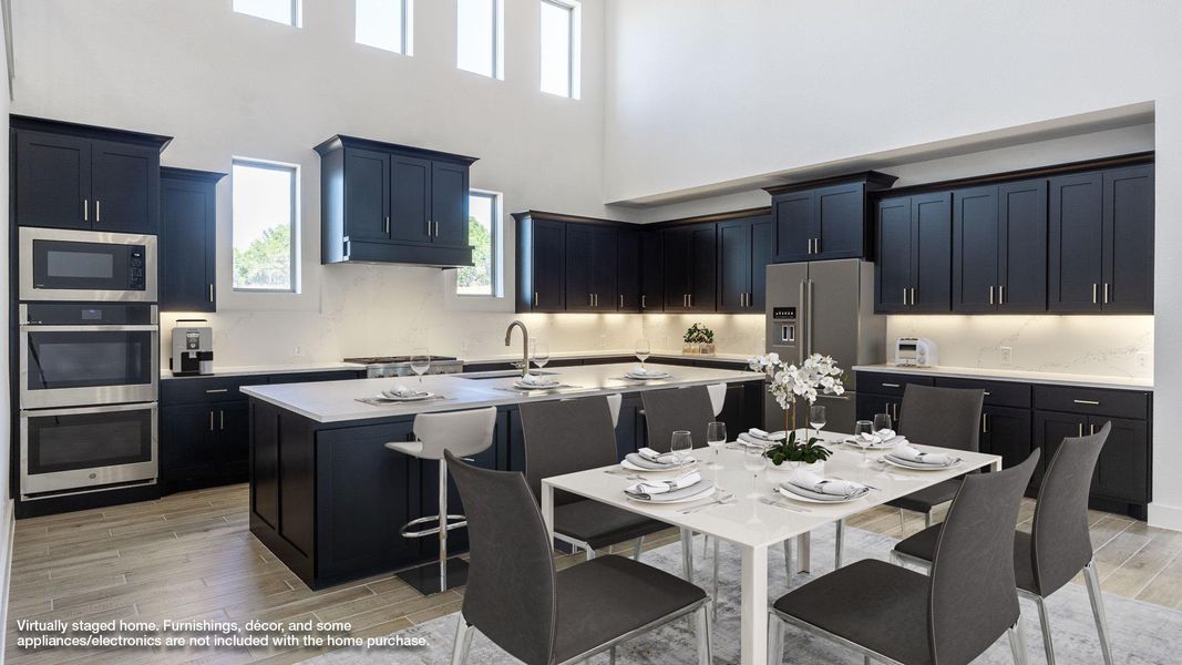 Kitchen featuring dark cabinets, wood tiled floors, stainless steel appliances, a kitchen island with sink, and a high ceiling