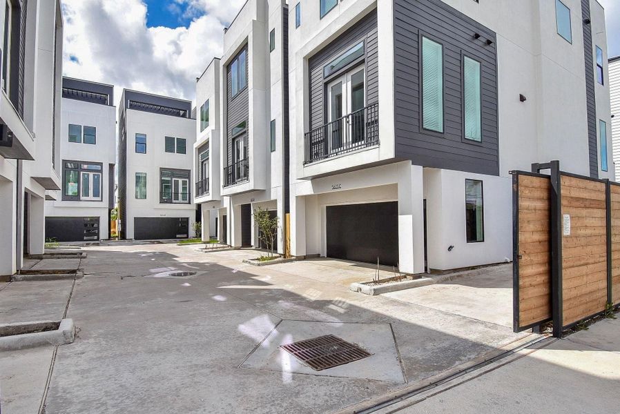 Modern property with a sleek, contemporary design, featuring white exteriors and dark accents. The gated community provides private driveways and garages, offering a blend of style and security.