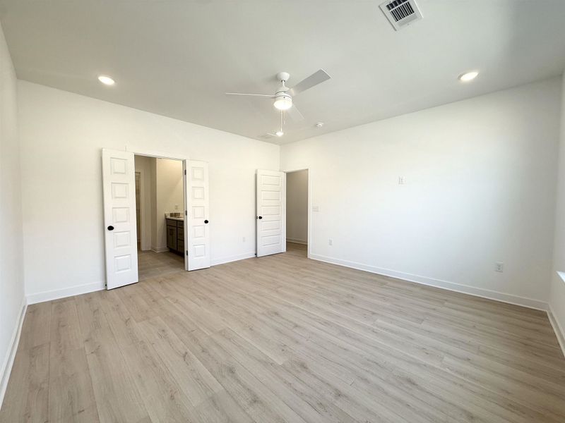 Unfurnished bedroom featuring recessed lighting, light wood-style flooring, ensuite bathroom, and a ceiling fan