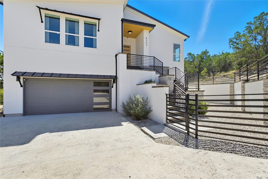Contemporary home featuring stucco siding, concrete driveway, a garage, and stairs