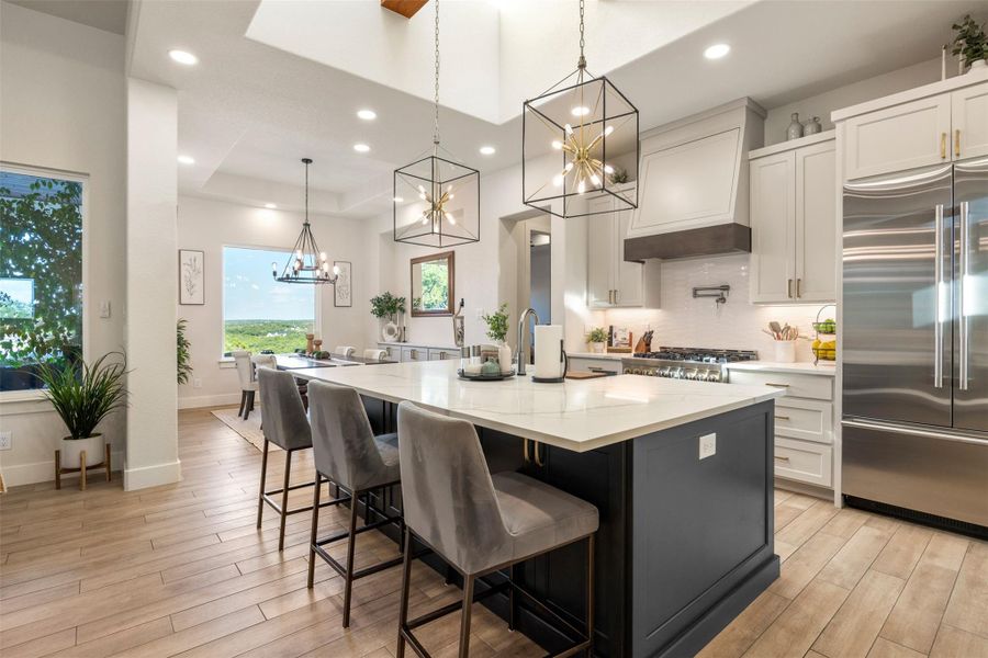 Kitchen featuring white cabinetry, a center island with sink, light stone countertops, and stainless steel built in refrigerator Kitchen featuring white cabinetry, a center island with sink, light stone countertops, and stainless steel built in refrigerator