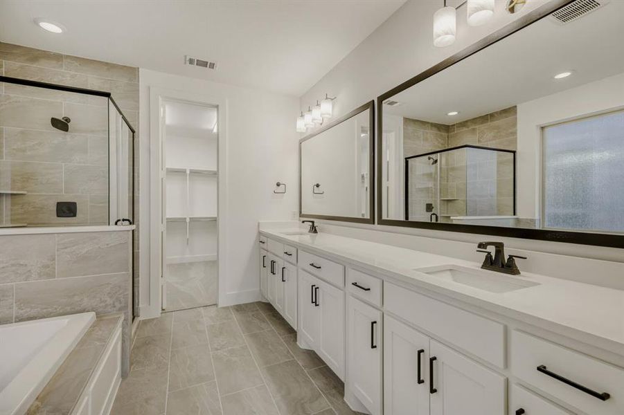 Full bath featuring double vanity, a bath, a shower stall, a spacious closet, and recessed lighting
