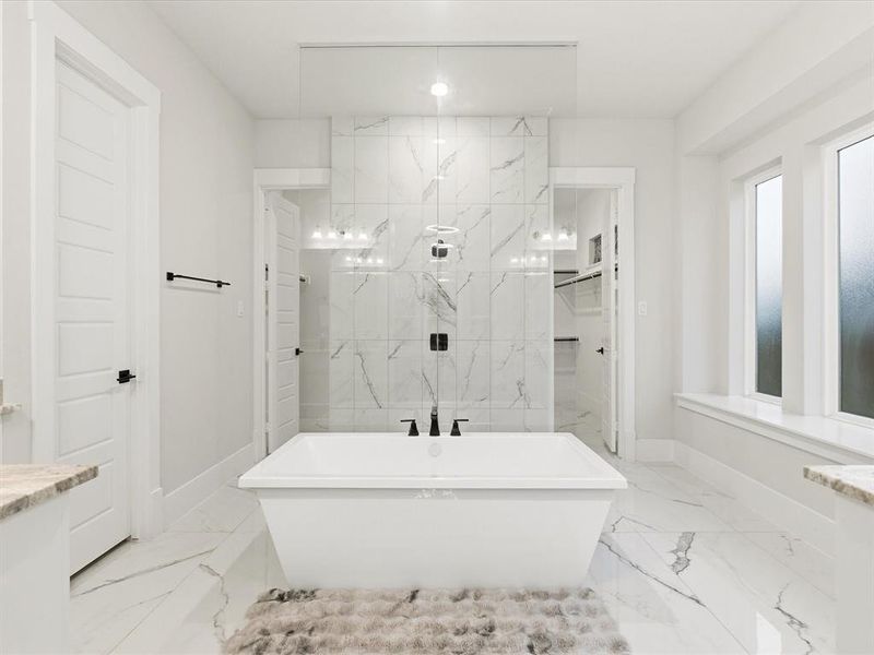 Freestanding soaking tub with matte black fixtures centered on a full-height tile accent wall Freestanding soaking tub with matte black fixtures centered on a full-height tile accent wall