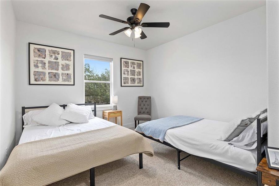 Carpeted bedroom with a ceiling fan and baseboards