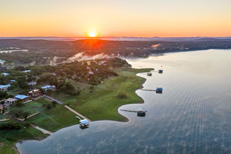Expansive waterfront property featuring multiple private boat docks, a verdant shoreline, and mature tree-lined hillsides under a clear sky Expansive waterfront property featuring multiple private boat docks, a verdant shoreline, and mature tree-lined hillsides under a clear sky