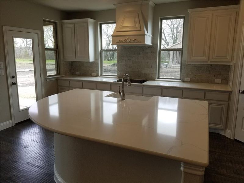 Kitchen has white cabinets, Monet Quartz counters, and mosaic tile decorative backsplash (different  than photo.)