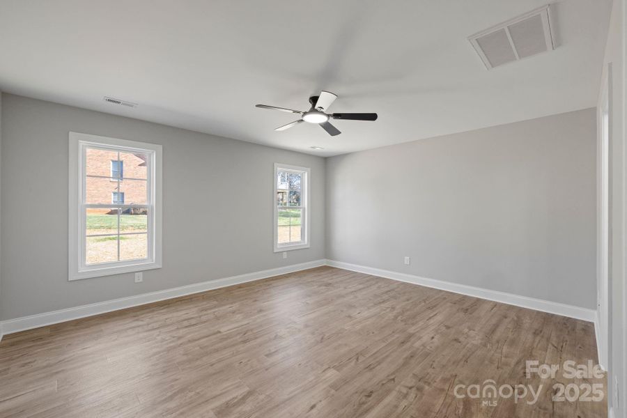 Spacious primary bedroom with large windows, soft natural light, and a modern ceiling fan offering a comfortable and serene retreat. Spacious primary bedroom with large windows, soft natural light, and a modern ceiling fan offering a comfortable and serene retreat.