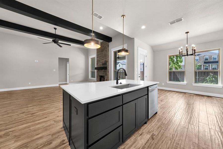 Kitchen with a center island with sink, dishwasher, a fireplace, light wood-type flooring, and sink