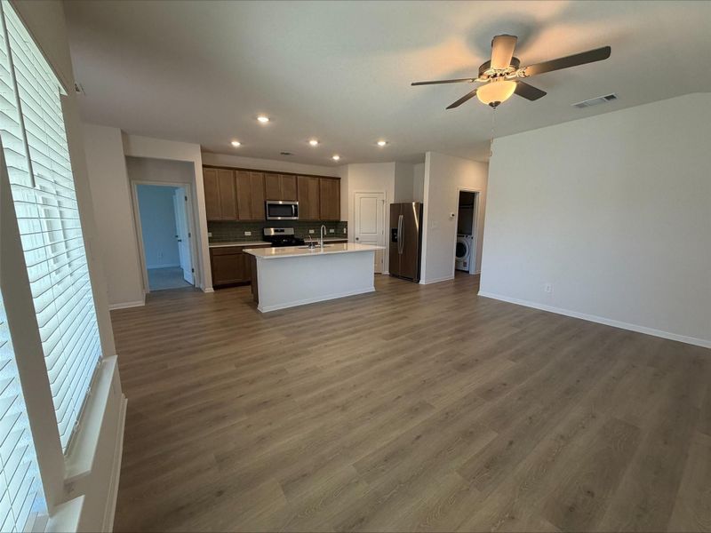 Kitchen with open floor plan, a kitchen island with sink, recessed lighting, appliances with stainless steel finishes, and dark wood finished floors