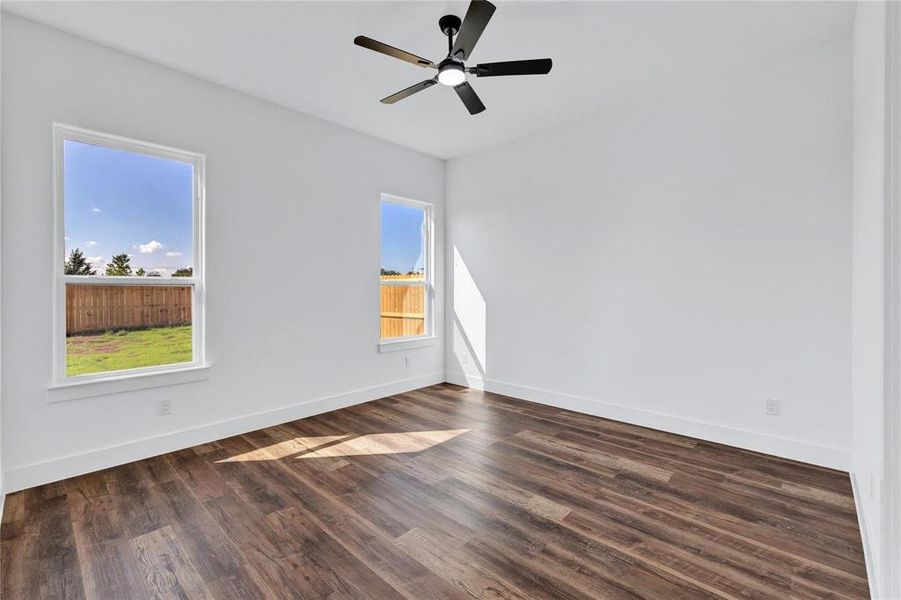 Empty room with dark wood-style floors and a ceiling fan