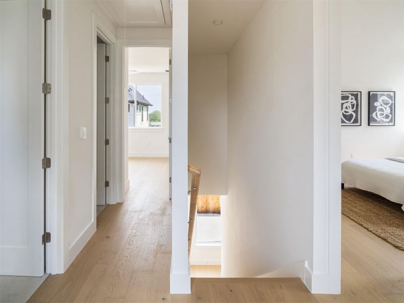 Hallway featuring wood-finish flooring, white walls, and bright overhead lighting