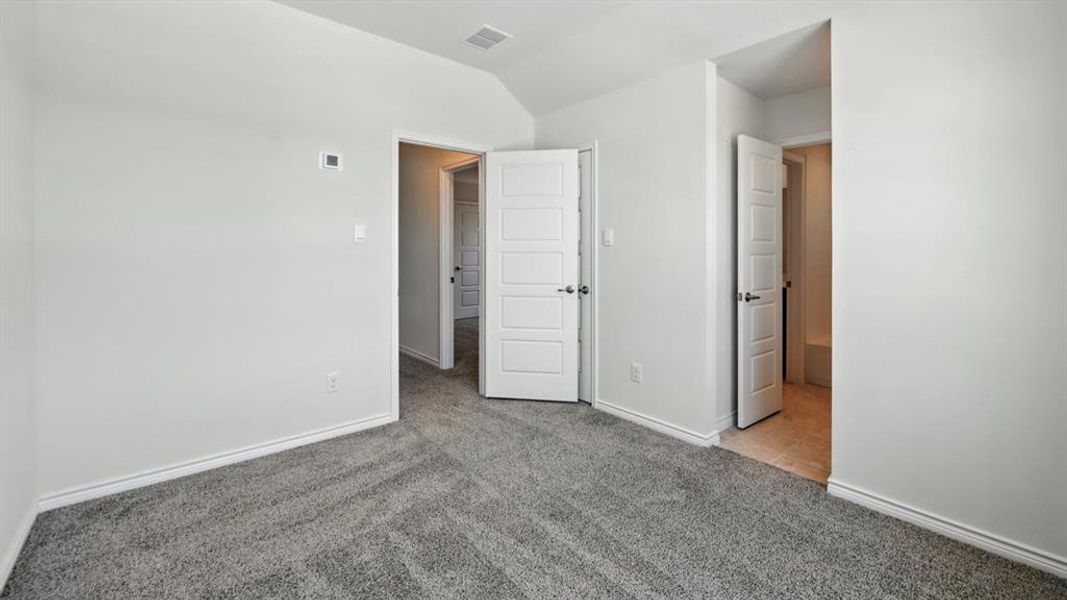 Unfurnished bedroom featuring light colored carpet and lofted ceiling
