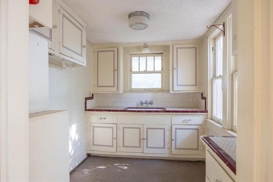 Kitchen featuring white cabinets, light colored carpet, and tile countertops