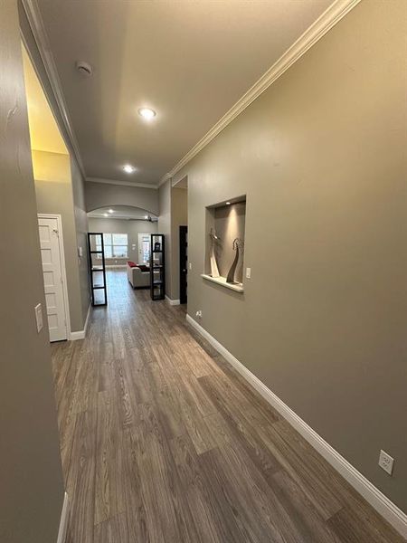 Hall featuring ornamental molding, arched walkways, dark wood finished floors, and recessed lighting
