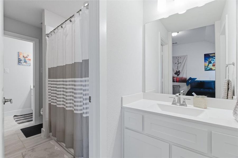Bathroom featuring a white vanity with an integrated sink, chrome faucet, and expansive wall mirror