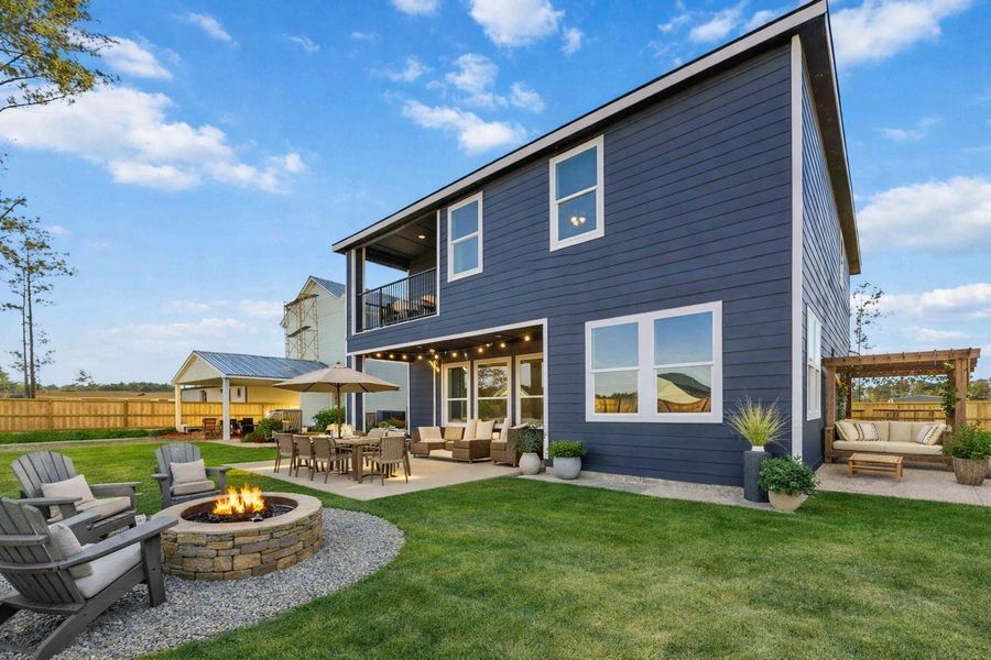 A beautifully virtually staged backyard designed for outdoor living, featuring a cozy fire pit, dining area, and covered lounge spaces