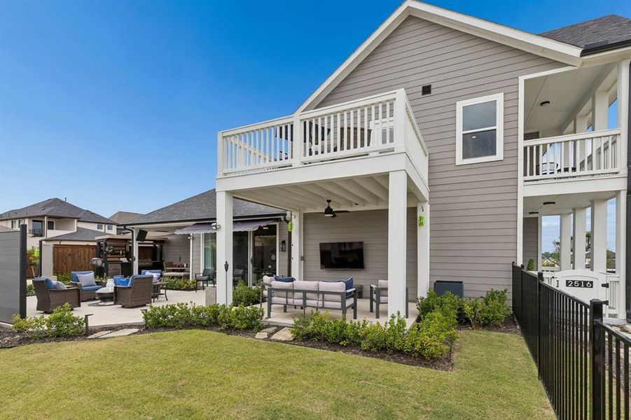 The covered outdoor living room extends your entertaining options with a wall-mounted television, ceiling fan, and comfortable gathering space designed for year-round enjoyment.