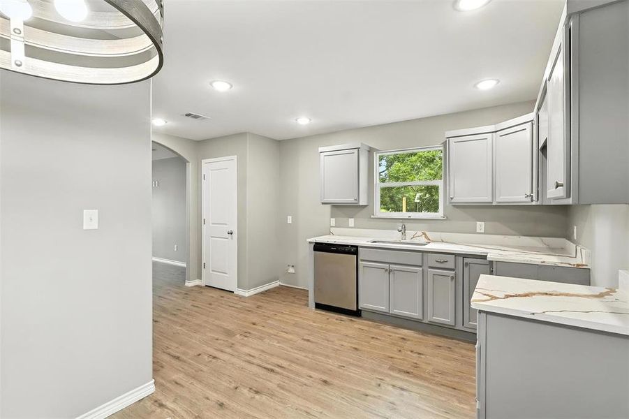 Kitchen featuring gray cabinets, arched walkways, dishwasher, light wood-type flooring, and recessed lighting Kitchen featuring gray cabinets, arched walkways, dishwasher, light wood-type flooring, and recessed lighting