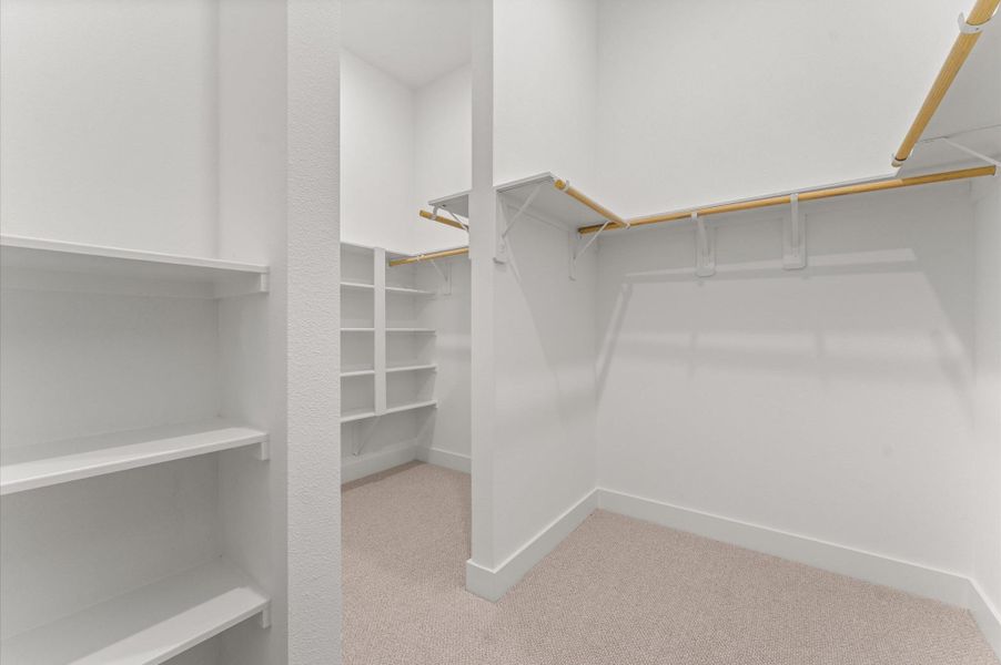 This expansive walk-in closet is a standout feature of the primary bedroom, offering generous space for wardrobe organization and personal storage. Thoughtfully designed shelving and hanging rods, the closet provides a boutique-like experience with room for everything from seasonal clothing to accessories. This expansive walk-in closet is a standout feature of the primary bedroom, offering generous space for wardrobe organization and personal storage. Thoughtfully designed shelving and hanging rods, the closet provides a boutique-like experience with room for everything from seasonal clothing to accessories.