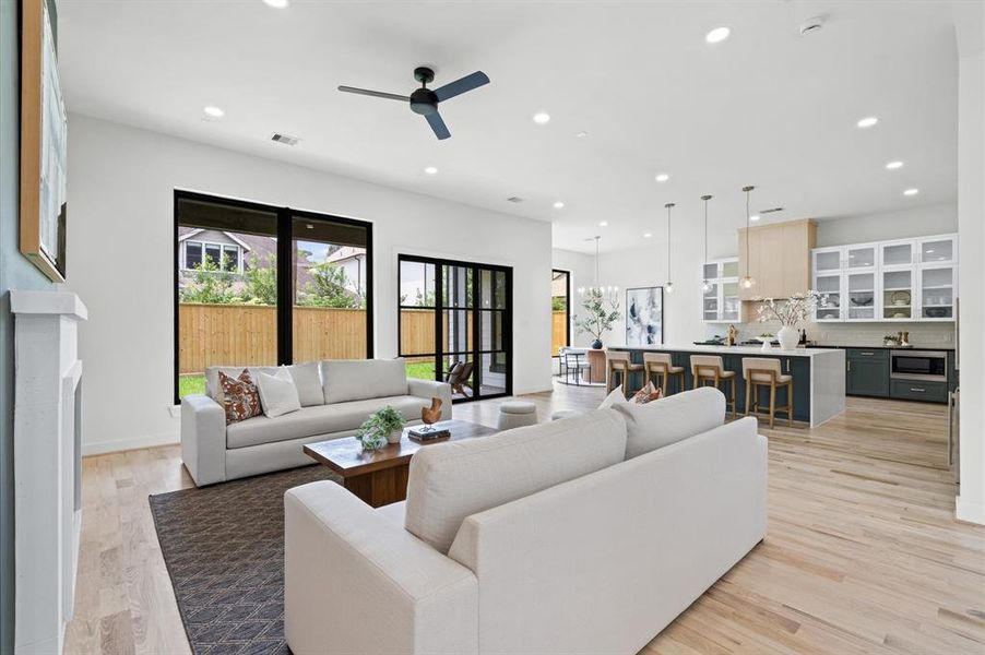 Modern open-concept living space with a seating area, large windows, and a kitchen with an island, showcasing a bright, minimalist interior design.