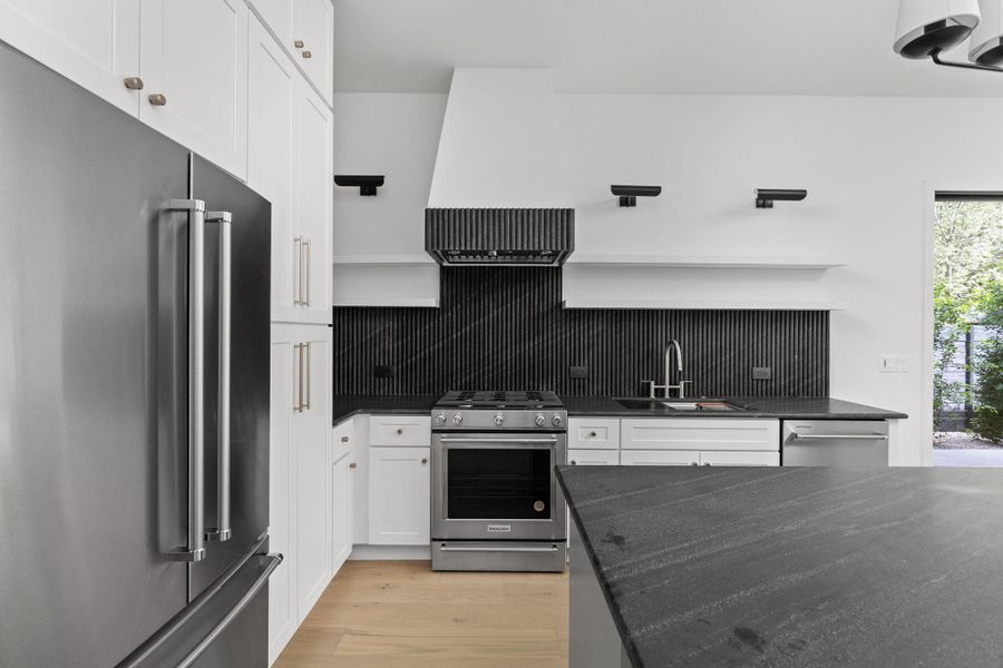 Kitchen featuring stainless steel appliances, open shelves, tasteful backsplash, white cabinets, and light wood finished floors