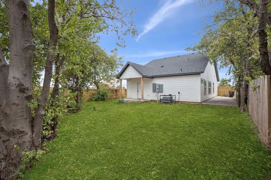 Back of property with a patio, roof with shingles, and a fenced backyard