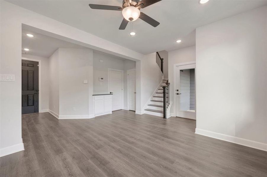 Spacious living area featuring wood-finish flooring, recessed lighting, and a ceiling fan with integrated lighting Spacious living area featuring wood-finish flooring, recessed lighting, and a ceiling fan with integrated lighting
