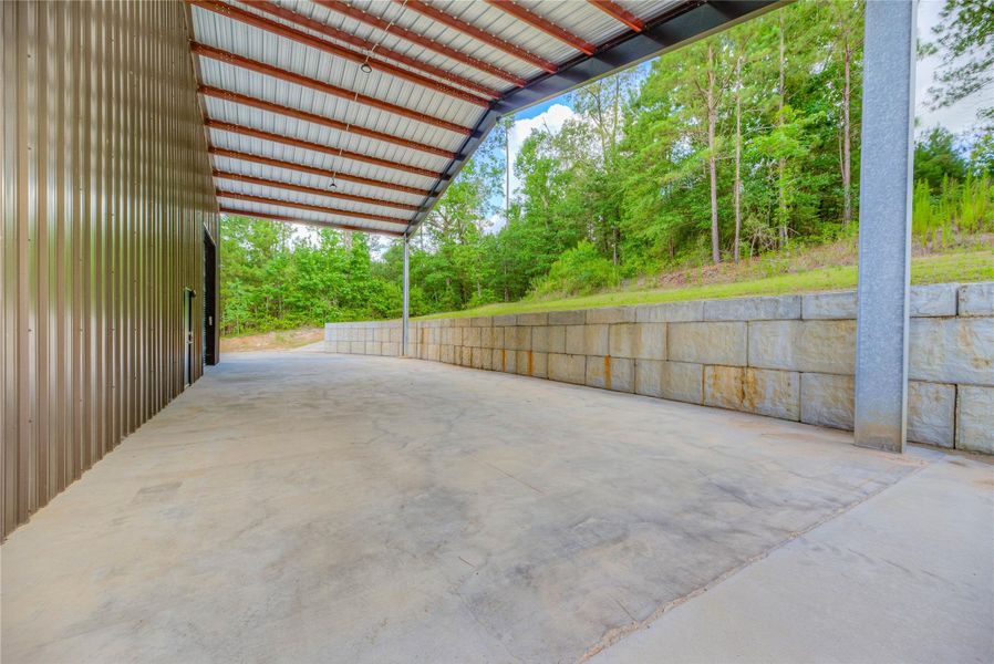 Attached carport area/ side of barndominium with a retaining wall Attached carport area/ side of barndominium with a retaining wall