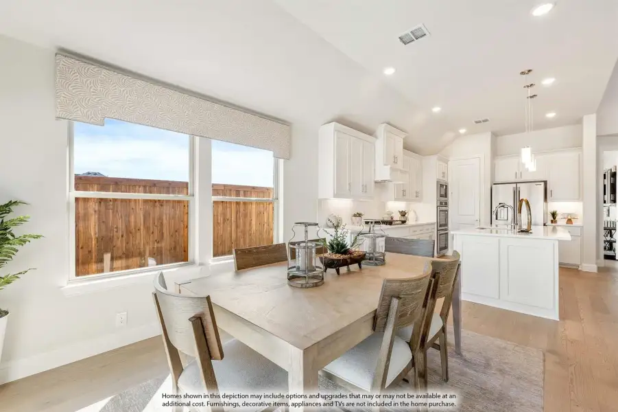 Open dining area with wood table and chairs, adjacent to white kitchen with island and hardwood floors