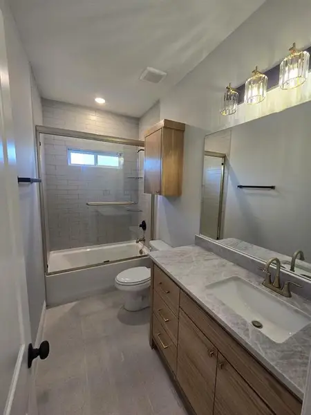 Full bathroom with vanity, shower / bath combination with glass door, light tile patterned flooring, and recessed lighting