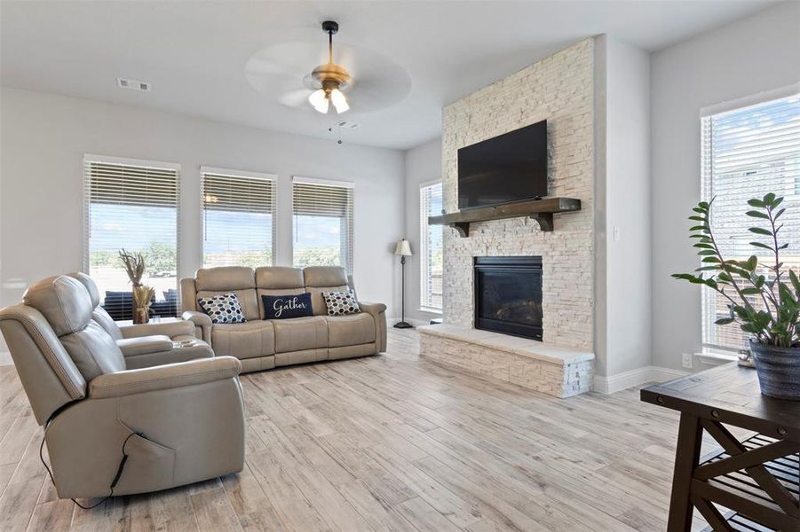 Living room with ceiling fan, a fireplace, and light hardwood / wood-style floors