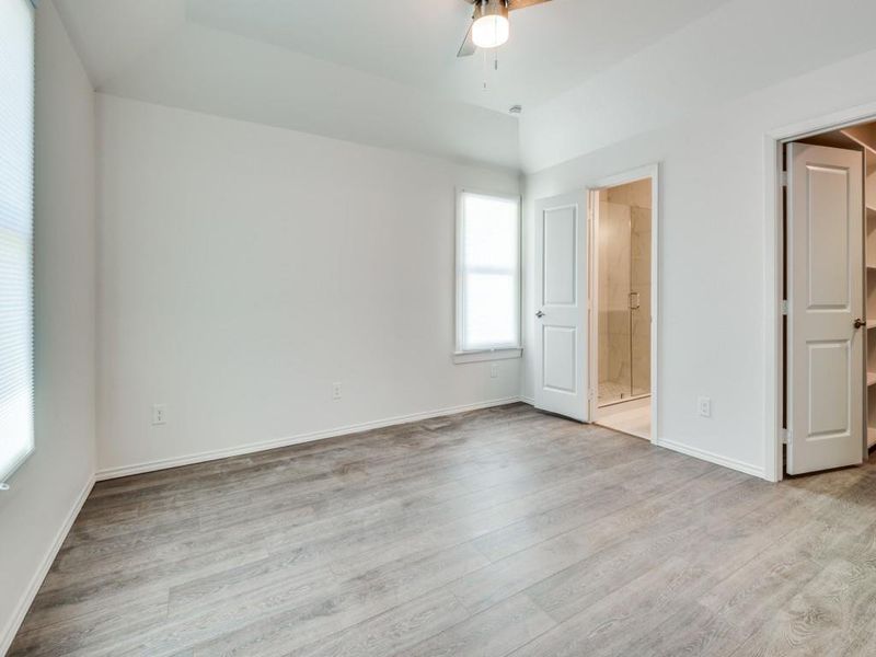 Unfurnished bedroom with ceiling fan, light wood-type flooring, and ensuite bathroom