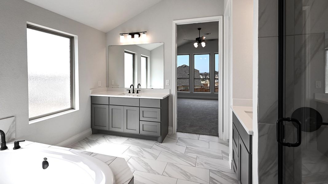 Full bath featuring a bathtub, marble finish floor, ceiling fan, vanity, and lofted ceiling Full bath featuring a bathtub, marble finish floor, ceiling fan, vanity, and lofted ceiling