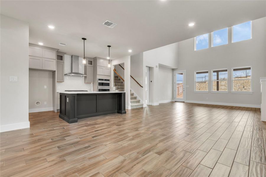 A spacious layout showcases a gourmet kitchen with a central island and a living area featuring high ceilings and abundant natural light.