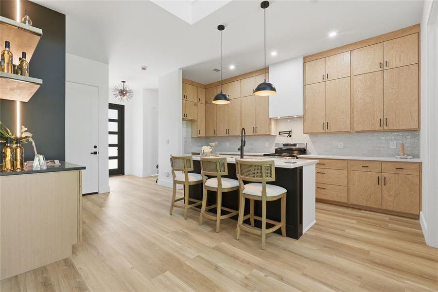 Modern kitchen featuring light wood-finish cabinetry, a central island with bar seating, and matte black pendant lighting