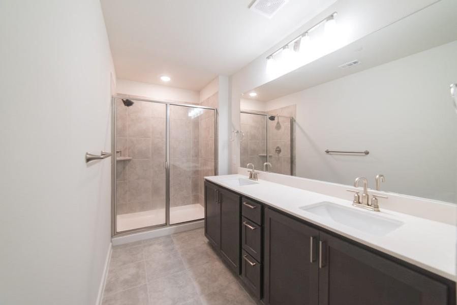 Full bathroom featuring double vanity, a shower stall, light tile patterned floors, and recessed lighting